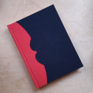 A black book with a red spine that has been shaped to form a bat shaped silhouette against the cover.