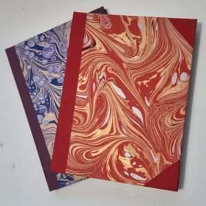 A pair of hard back books with spines and corners covered in book cloth and the rest covered in marbled paper.